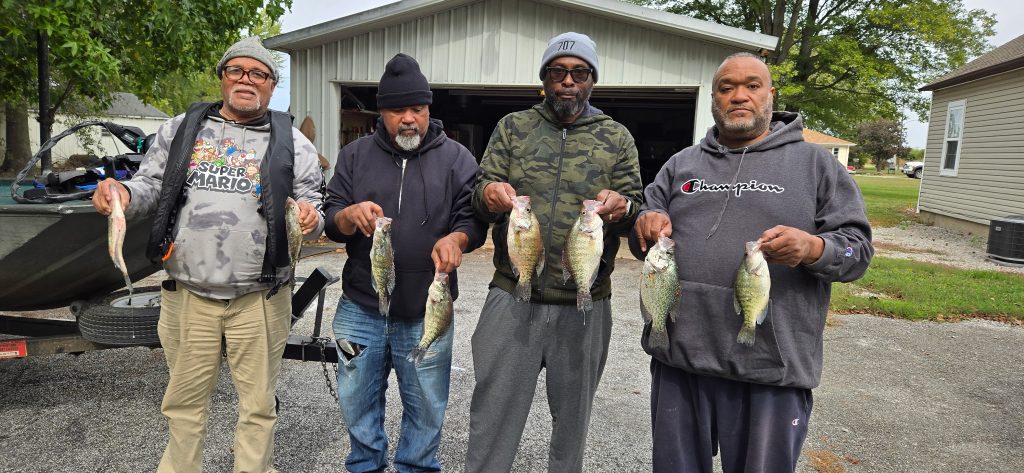 Four customers holding crappie with the Airbnb and fishing boat visible