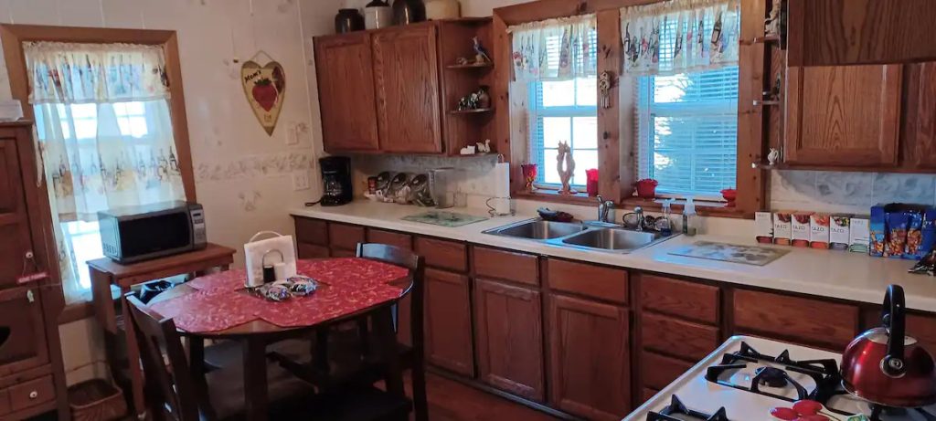 Fully stocked kitchen with stove, coffee maker, teapot, microwave, dining table, and refrigerator in Rend Lake Airbnb vacation rental