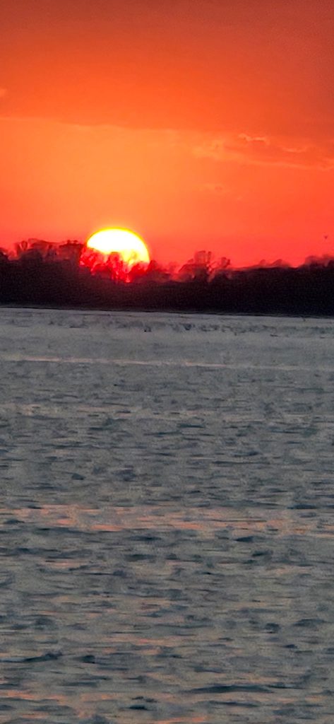 Bright orange sunset over Rend Lake with silhouetted shoreline and calm lake water