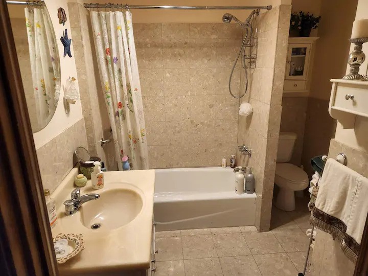 Full bathroom with bathtub and shower, vanity, mirror, toilet, and towels