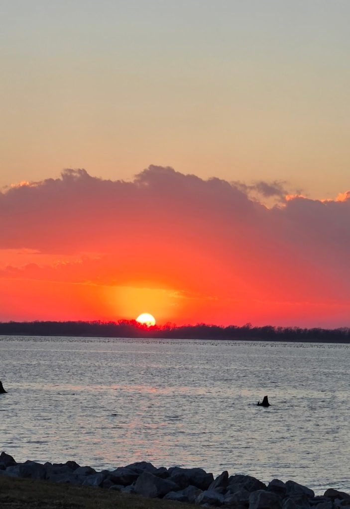 Colorful sunset over Rend Lake with orange, yellow, purple, and blue skies