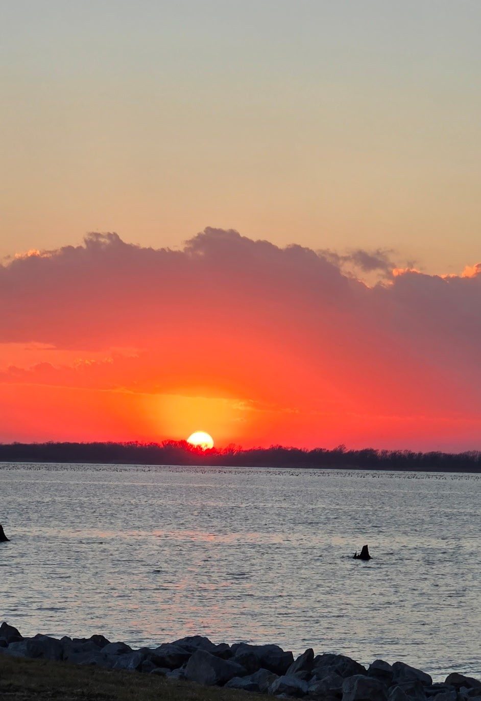 Colorful sunset over Rend Lake with orange, yellow, purple, and blue skies